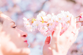温暖春日一位美女正手捧一簇盛开的樱花